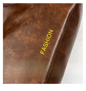 Detailed macro shot of brown pebble grain leather tote with yellow FASHION text design