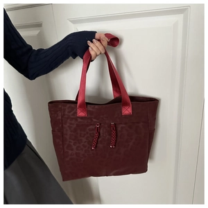 Vue détaillée du sac cabas bordeaux avec motif léopard et ornements de pompons