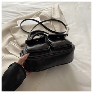Detail view of black vintage bowling bag with front pockets on a chic beige blazer