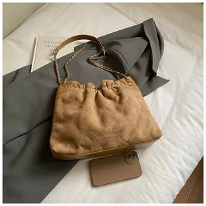 Braune Wildledertasche mit goldener Kette, gestepptem Muster neben einem Smartphone