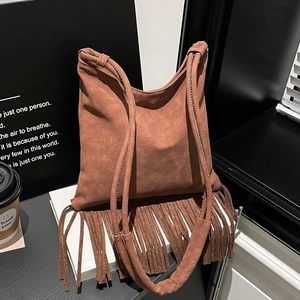 Sac à épaule en daim marron avec longues franges bohèmes sur socle d'exposition