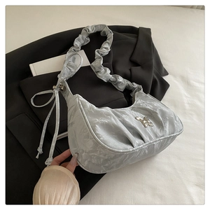 Detail of silver pleated crescent bag featuring metallic butterfly and scrunchie strap