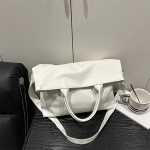 Retro white lychee leather tote bag with shoulder strap on a black desk setting