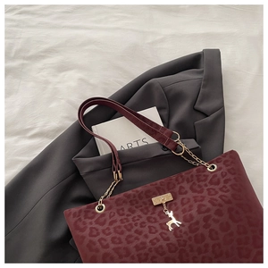 Dettaglio della borsa tote leopardata bordeaux con catena dorata e pendente a cervo