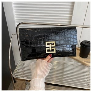 Close-up of black crocodile embossed envelope clutch bag with gold geometric metal clasp