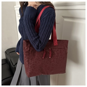 Fashionable burgundy leopard print tote bag featuring stylish red shoulder straps and tassels