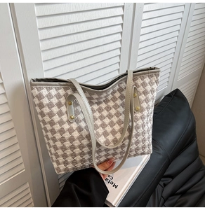 Detail of woven houndstooth fabric pattern on a large tote bag with silver metallic studs