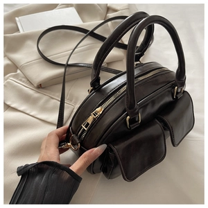 Detail view of dark coffee leather bowling bag with twin flap pockets and gold hardware