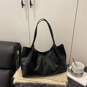 Minimalist black tote bag with large capacity shown on a cozy knit scarf with urban decor