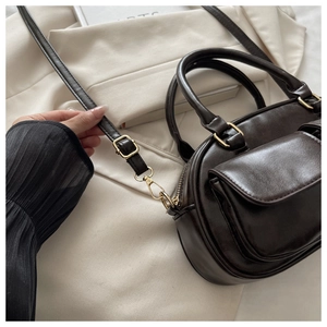 Detail view of dark brown PU leather shoulder bag with gold hardware and front pocket