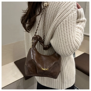 Detail of vintage brown pleated dumpling bag with woven metal chain strap for women