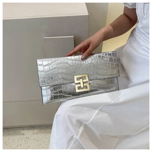 Detail shot of silver faux crocodile leather envelope clutch bag with gold interlocking lock