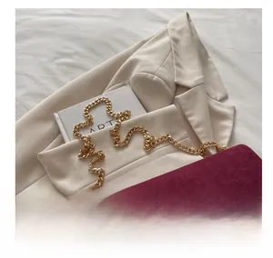 Detailed close-up of burgundy suede crossbody bag featuring a thick gold chain strap