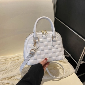 White quilted shell handbag with gold zippers and detachable strap in a hand-held display