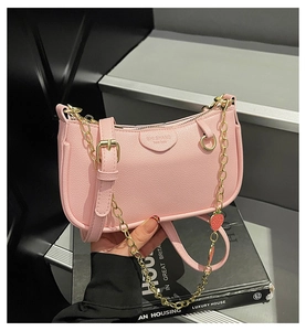 Detail of pink lychee textured baguette bag with gold chain and strawberry charm