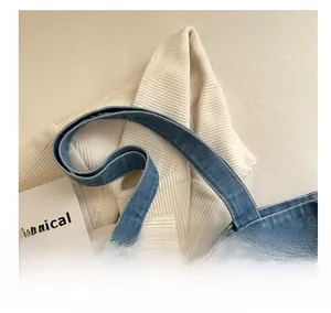 Detailed close-up of blue denim tote bag handle showing high-quality stitching and texture