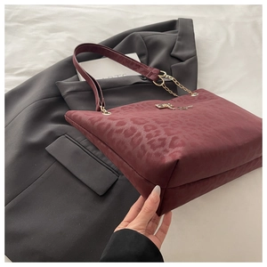 Dettaglio della borsa tote leopardata bordeaux con catena dorata e chiusura in metallo