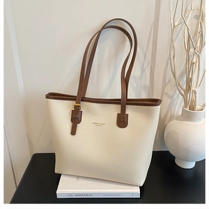 Detail of a minimalist cream tote bag with brown straps and elegant gold lettering