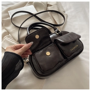 Detailed view of dark brown crossbody bag featuring front pockets with magnetic gold buckles
