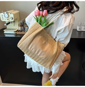 Détail d'un grand sac cabas en paille tissé avec écusson en cuir beige et texture douce