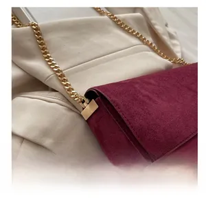 Detailed close-up of the polished gold hardware on a burgundy suede crossbody bag