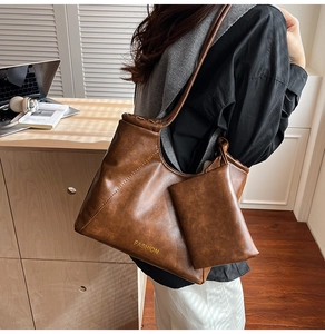 Close-up of large brown leather tote bag with small pouch and fashion lettering detail