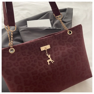 Dettaglio della borsa tote bordeaux leopardata con catena dorata e ciondolo a cervo