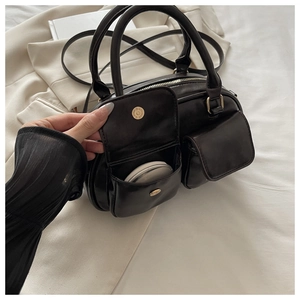 Detail of front flap pockets on black leather bowling bag showing practical storage