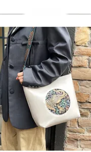 Detail of white leather shoulder bag with vintage elephant relief and ethnic strap