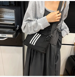 Dettaglio della borsa a tracolla in nylon nero con tre strisce bianche verticali
