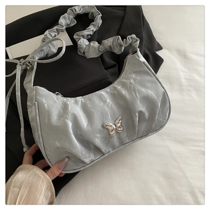 Close-up of silver crescent bag with pleated fabric and metallic butterfly detail