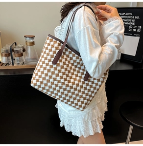 Detail of woven tote bag featuring brown and cream check pattern and leather straps