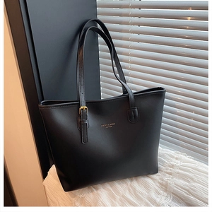 Close-up of black matte tote bag with adjustable shoulder strap and gold hardware accents