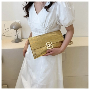 Elegant gold crocodile texture clutch bag with metallic geometric clasp held by model