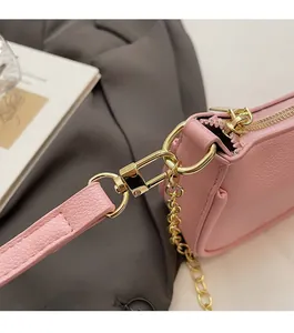Detailed close-up of pink litchi grain leather bag with high-shine gold chain hardware
