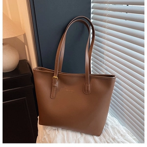 Detail of large brown tote bag showing gold buckle adjustment and leather texture