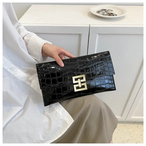 Close-up of black crocodile texture envelope clutch bag with large gold geometric buckle
