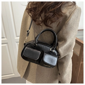Detailed view of black Boston bag featuring dual front pockets and glossy leather finish