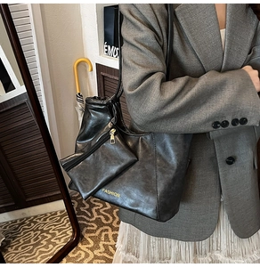 Modern black oversized tote bag with gold lettering shown on model with chic outfit