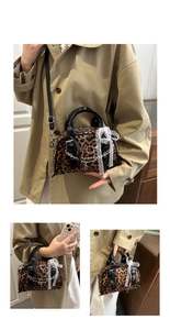 Detail of leopard print baguette bag with silver chains, lace bow and shiny black handles
