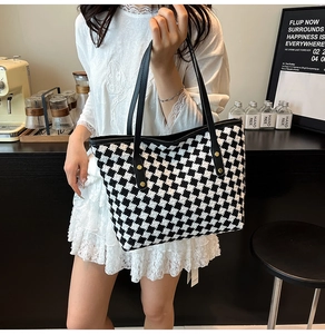 Detailed view of checkered woven tote bag with black leather straps and gold rivets