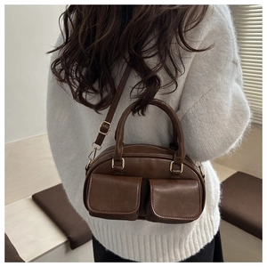 Close-up of a vintage dark brown shoulder bag with dual flap pockets and metal buckle