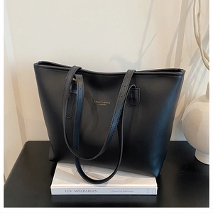 Detail of matte black tote bag with gold logo placed on a classic book for a premium look