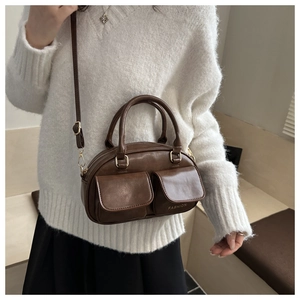 Close-up of dark brown leather tote bag with dual front flap pockets and fashion text