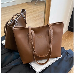 Detailed texture of brown PU leather tote bag with gold lettering in lifestyle setting