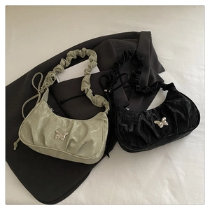 Detail of ruched crescent underarm bags in black and green with silver butterfly charms