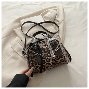 Detail of leopard print handbag with silver chains, lace bows, and metal cross charms