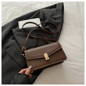 Detailed view of the dark brown matte leather bag with a gold buckle on a stylish suit
