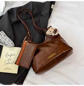 Close-up of vintage brown tote bag with fashion print and plush leopard cat charm