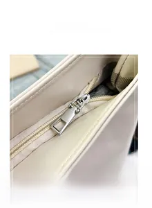 Detailed macro view of the silver metal zipper and smooth leather texture of the beige tote